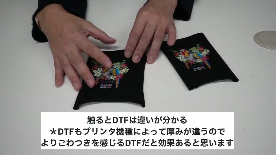 DTFでプリントした黒い小さなTシャツ2枚を手で触って比べているところ