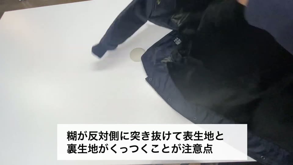 コーチジャケットの裾をめくって裏地を見せている様子と、糊が反対側に突き抜けて表生地と裏生地がくっつくことが注意点というテロップ