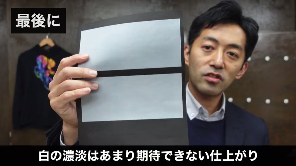 黒い紙にK100からK40程度まで段階的に白を印刷した帯を見せている様子
