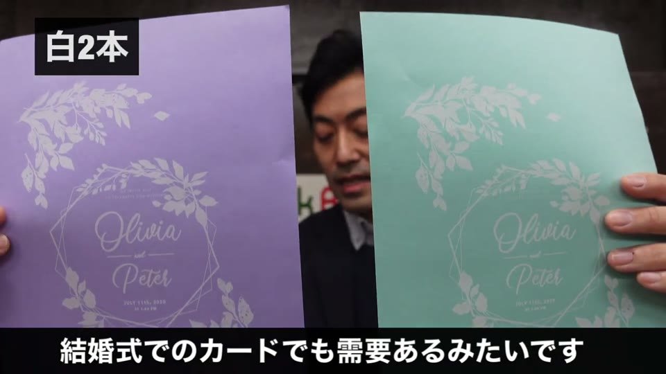 紫と緑の色画用紙に、白で花の輪とOlivia Peterの名前を印刷した結婚式のカード
