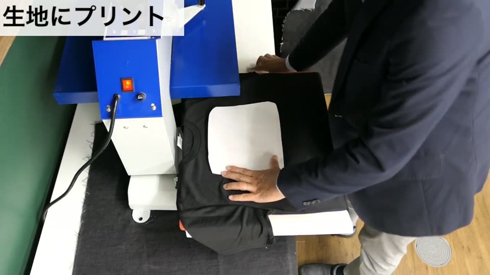 プレス機の下ゴテにかぶせた黒のドライTシャツに、4辺を切った転写マークをのせている様子