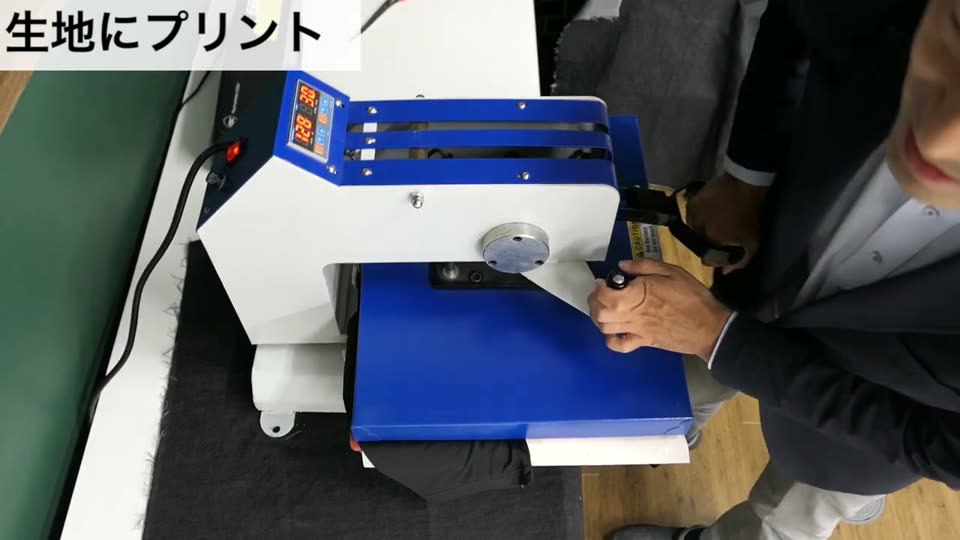 スウィング式の熱プレス機を下ろして黒のドライTシャツにプレスしている様子