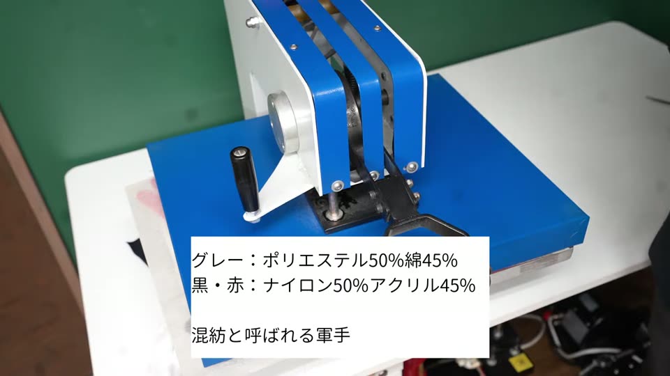 プレス機で軍手をプレスしている様子。テロップはグレーはポリエステル50%綿45%、黒と赤はナイロン50%アクリル45%、混紡と呼ばれる軍手