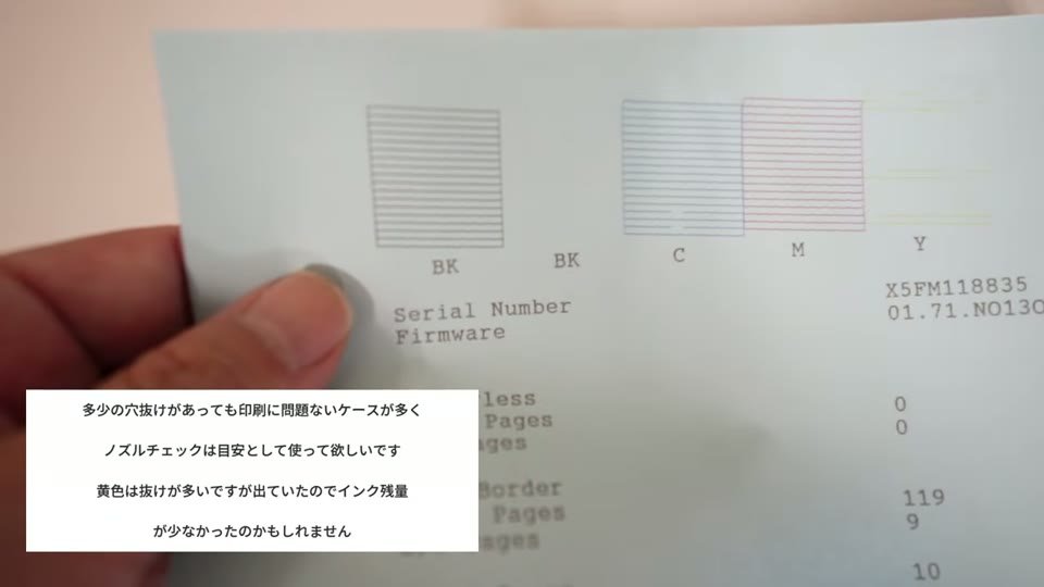 色紙に印刷したノズルチェックのパターンを手に持ち、白と黄色の抜けを確認している様子