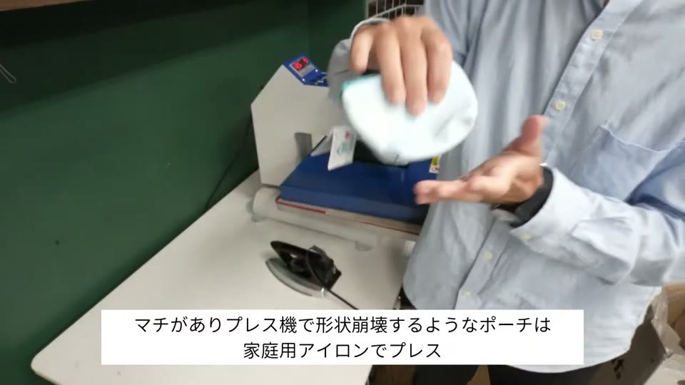 マチのある水色のポーチを手に持って説明している様子。テロップに「マチがありプレス機で形状崩壊するようなポーチは家庭用アイロンでプレス」