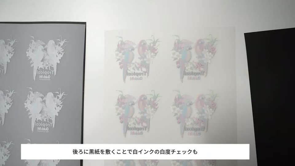 パウダーを付けたDTFフィルムの後ろに黒い紙を敷き、白インクとパウダーの乗り方を確認している様子
