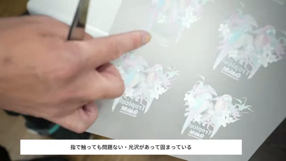 ベイキングを終えたDTFフィルムのデザイン部分を指で触り、光沢があって固まっていることを確かめている様子