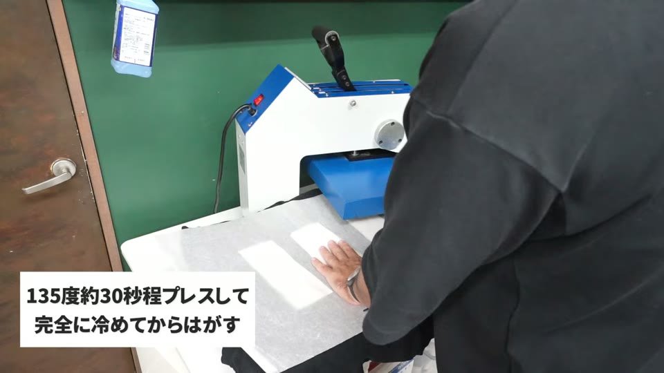 黒いTシャツにタイプWの転写シートを置き、プレス機で135度約30秒プレスしている様子