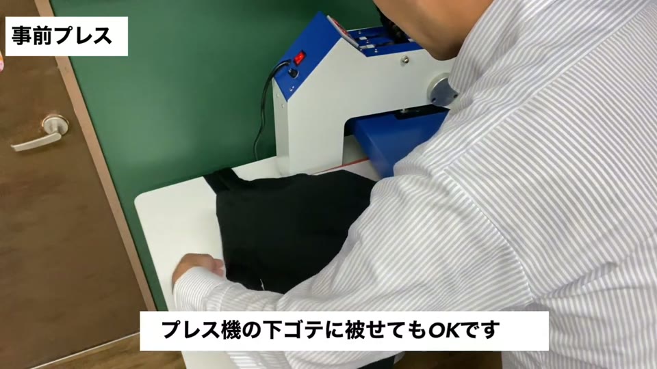 黒いロンTをプレス機の下ゴテにかぶせて事前プレスの準備をしている様子。プレス機の下ゴテに被せてもOKですとテロップが出ている