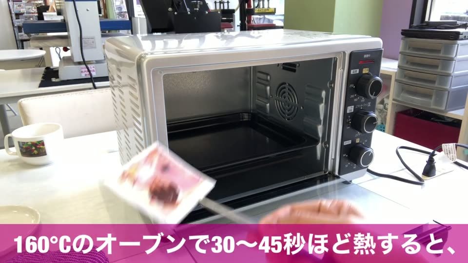 切り取った写真のシートをピンセットで持ち、オーブンで160℃30〜45秒ほど熱しているところ
