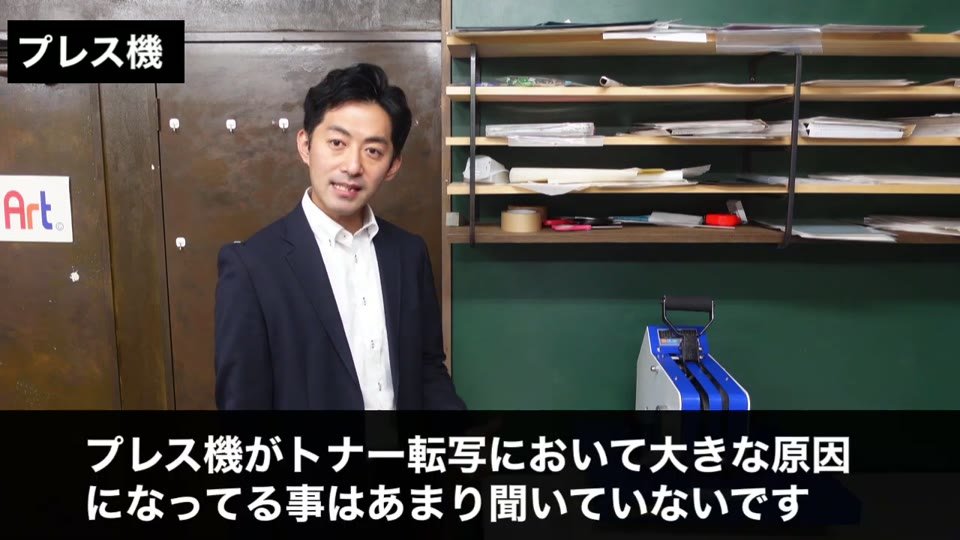 プレス機の前で「プレス機がトナー転写において大きな原因になってる事はあまり聞いていないです」と説明している場面