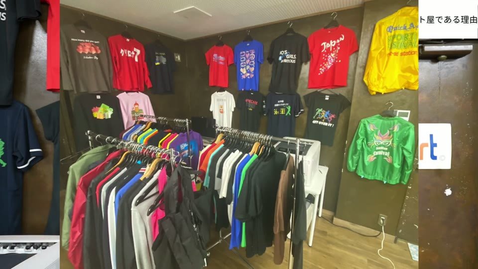 ショールームの壁とラックに、白トナーでプリントしたTシャツやジャケットがたくさん並んでいる様子