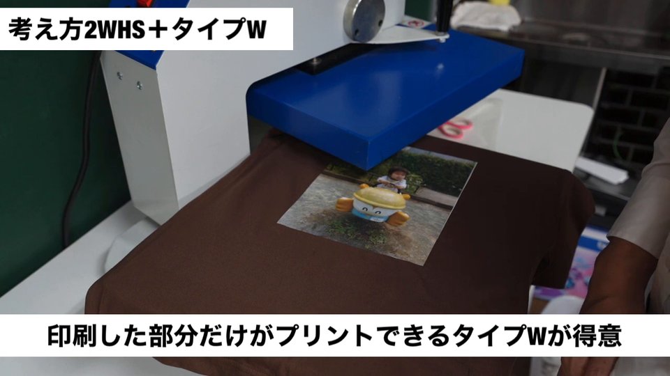 茶色のTシャツにWHSの写真を置き、その下に文字用の抜ける転写紙を置いてプレス機にセットしている様子