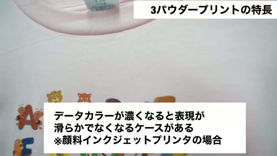 ピンクのTシャツにパウダープリントしたアルファベットと動物の柄を指でさし、データカラーが濃くなると表現が滑らかでなくなるケースがある、顔料インクジェットプリンタの場合というテロップ