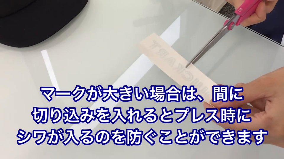 横長の転写紙にはさみで切り込みを入れている。テロップ:マークが大きい場合は、間に切り込みを入れるとプレス時にシワが入るのを防ぐことができます