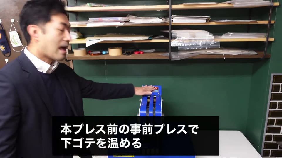 本プレス前の事前プレスで下ゴテを温めるとテロップが出ている場面。プレス機のハンドルに手をかけている