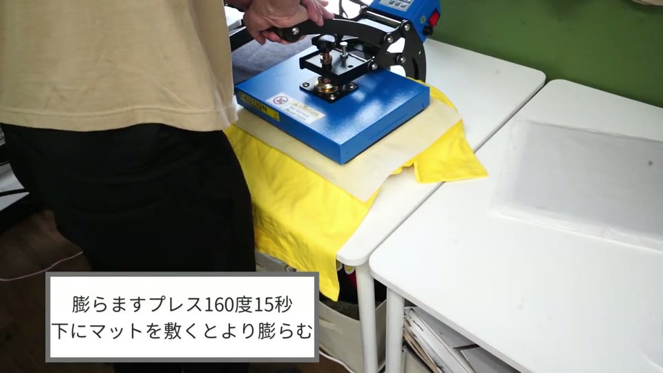 黄色いTシャツの下にマットを敷き、プレス機で膨らませるプレスをしているところ