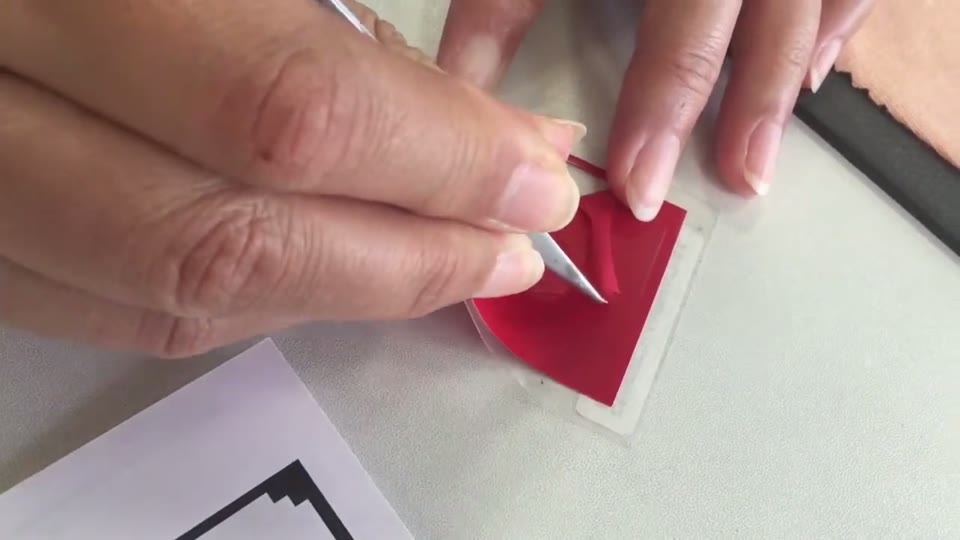 赤いラバーシートの切り込みに、ピンセットを入れて不要な部分をめくっているところ