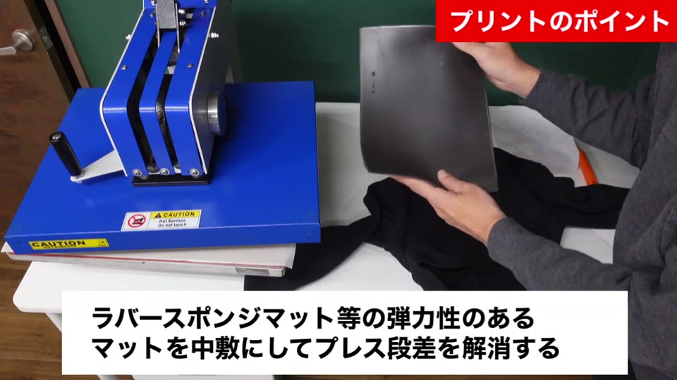 黒いパーカーの中にラバースポンジマットを入れようとしている様子。ラバースポンジマット等の弾力性のあるマットを中敷にしてプレス段差を解消するとテロップが出ている