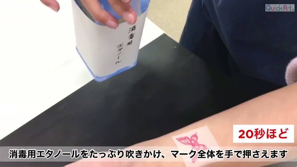 フィルムを腕にのせ、上から消毒用エタノールをたっぷり吹きかけている。20秒ほどの表示