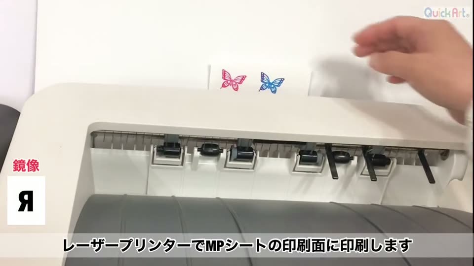 レーザープリンタから、ちょうちょのデザインを鏡像で印刷したMPシートが出てくるところ