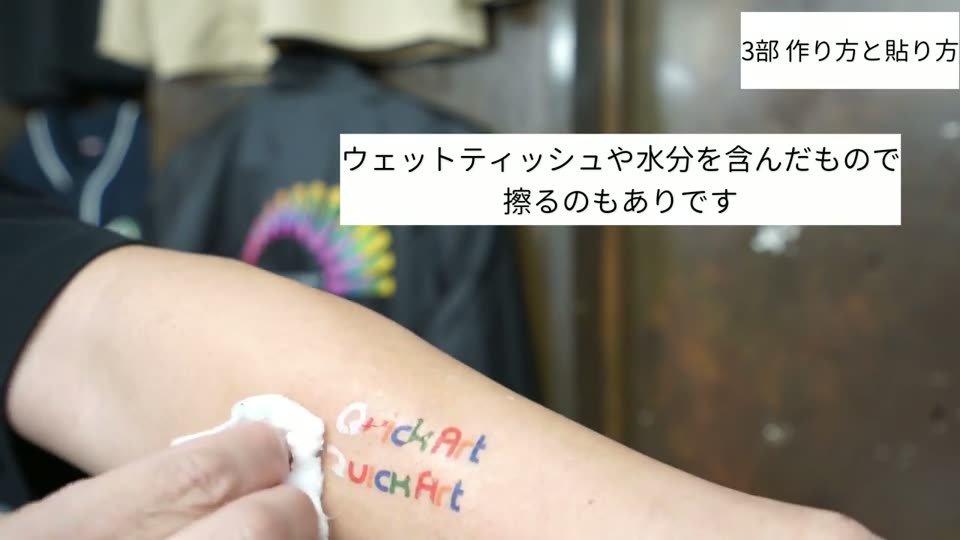 腕に貼ったタトゥーシールを、水分を含んだウェットティッシュでこすって取っているところ