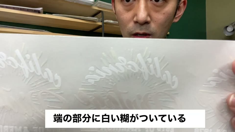 糊付けを終えた転写シートの端を手前に見せ、端の部分に白い糊がついていると字幕が出ている様子