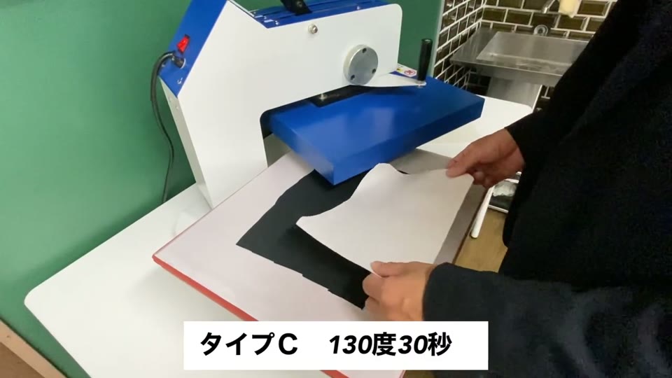 黒いポリエステル生地にタイプCのマークシートを乗せてプレス機でプレスするところ
