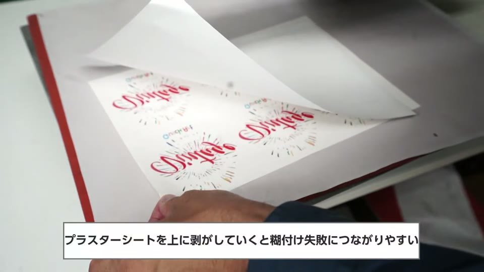 糊シートを上に持ち上げるように剥がしている手元と、プラスターシートを上に剥がしていくと糊付け失敗につながりやすいの字幕