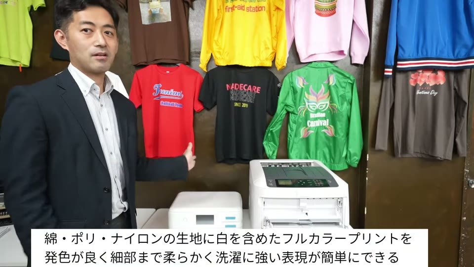 白トナープリントのTシャツやジャンパーの前で、綿・ポリ・ナイロンの生地に白を含めたフルカラープリントを発色良く細部まで柔らかく洗濯に強い表現が簡単にできると説明するテロップ