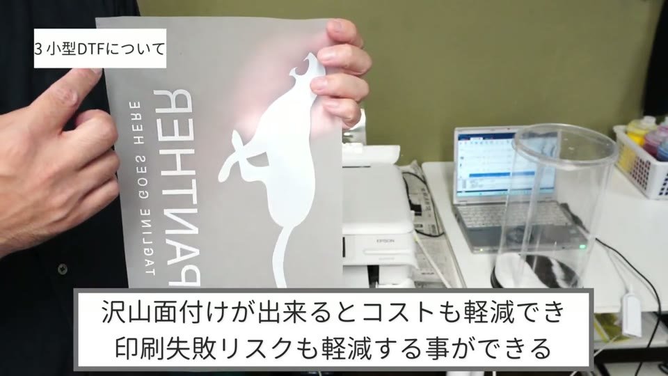パンサーのイラストと小さなイラストを面付けして印刷したDTFのフィルムを持っている様子