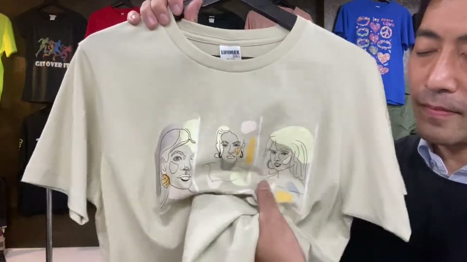 生成りのTシャツのプリント部分を、手でくしゃっと寄せて見せている場面