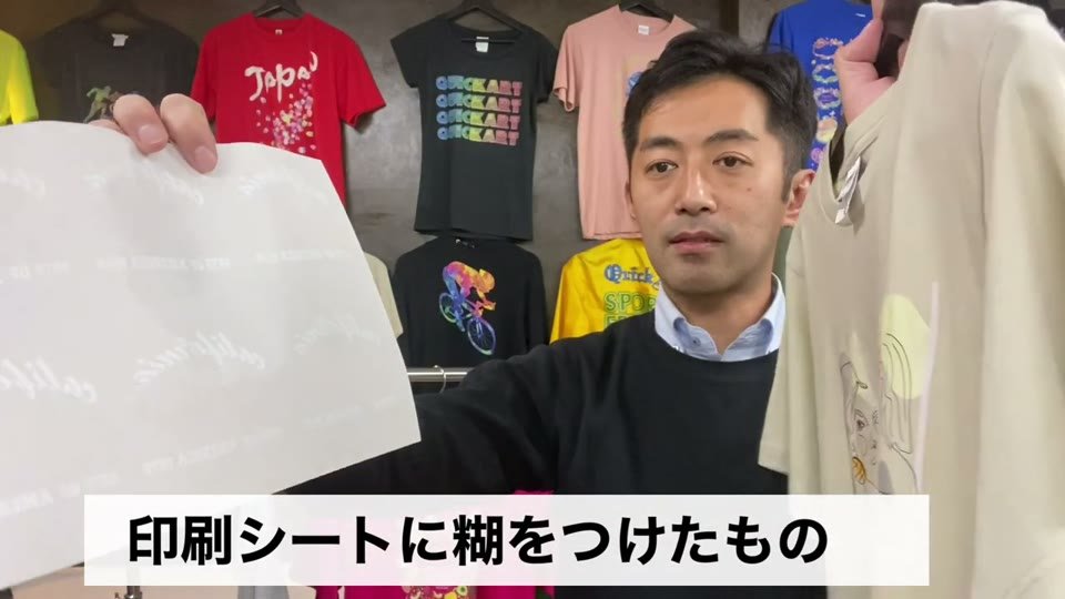 糊を付けたマークのシートを手に持ち、「印刷シートに糊をつけたもの」とテロップが出ている場面