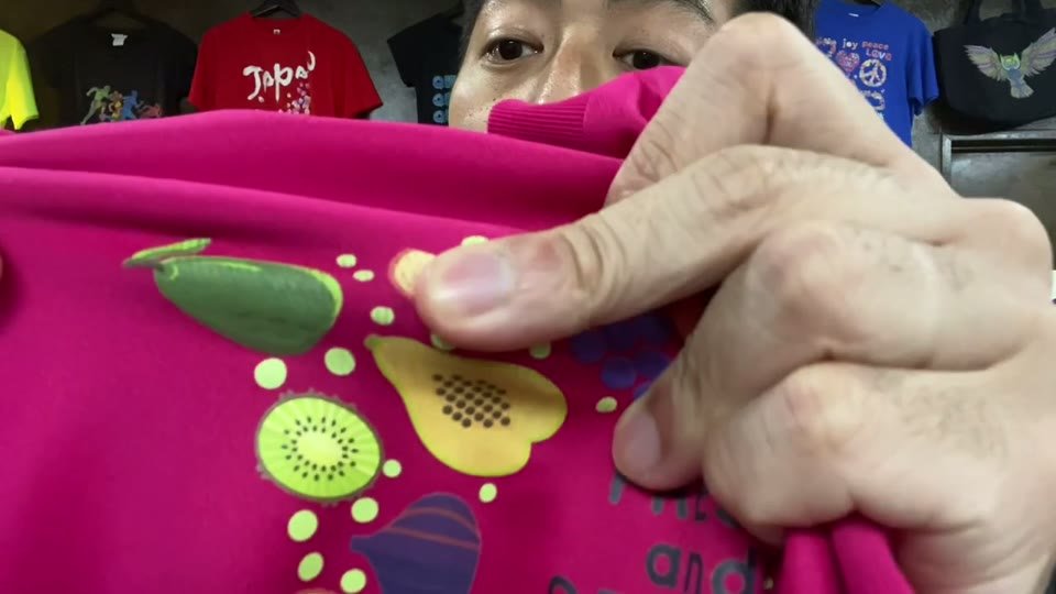 ピンクのTシャツのフルーツのイラスト部分を、指でつまんで伸ばしている場面