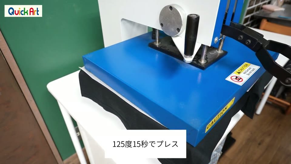 黒いTシャツにWHS-CLを置き、フォースインペーパーをのせてプレス機を閉じたところ。「125度15秒でプレス」のテロップ