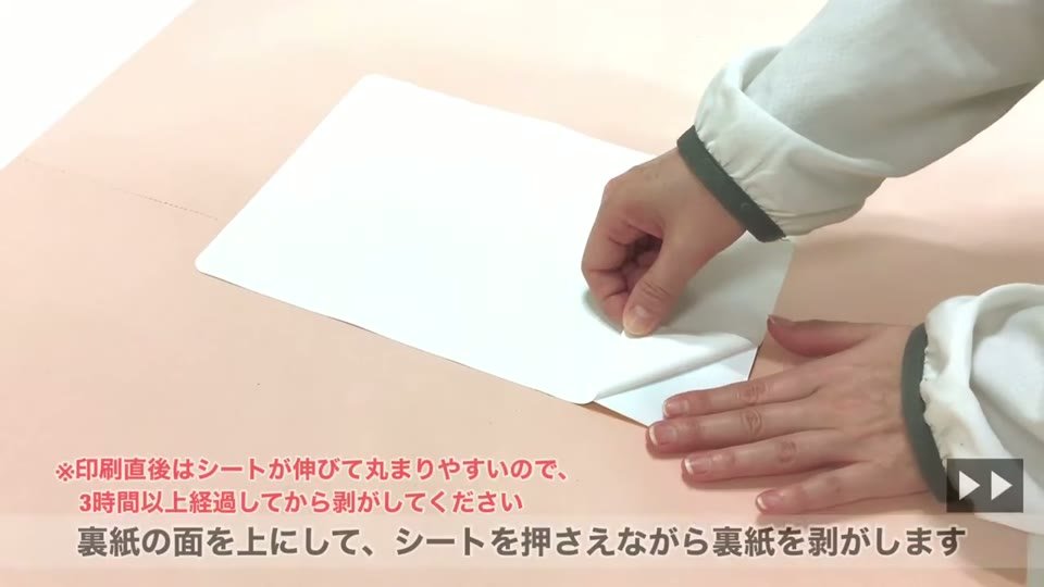 裏紙の面を上にしたWHS-SOFTを手で押さえながら、裏紙を剥がしているところ