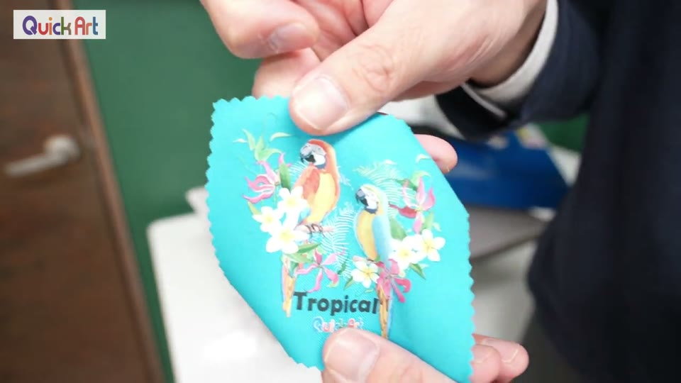 水色の布にプレスしたTropicalのオウムのイラストを手に持って見せている