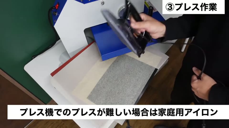 プレス機の上で、木材に当てたマークの上から家庭用アイロンを当てている